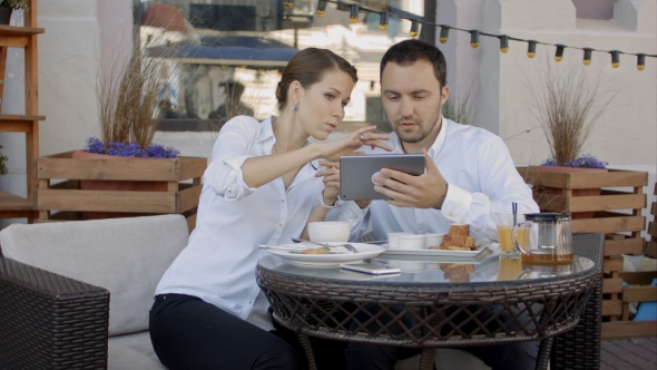 Two Young Business People Using Digital Tablet On a Meeting At Coffee Shop