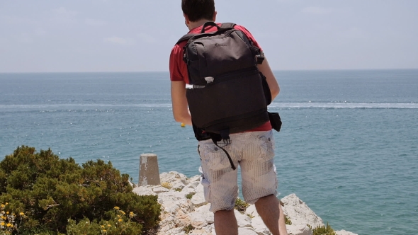 Young Man With Backpack Run To The Edge And Looks At The Stunning Views.