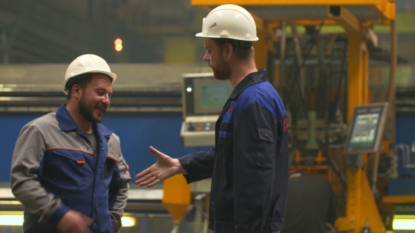 Two Engineers Smile, Laugh And Shake Hands In Heavy Industry Factory