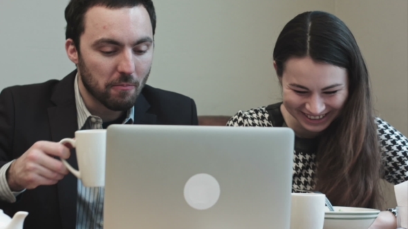 Colleagues At Cafe Looking On Laptop Screen And Laughing