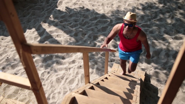 Man Climbing Up Ladder On Tree House At The Beach