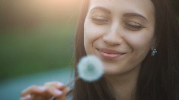 Smiling Woman Blowing On a Dandelion
