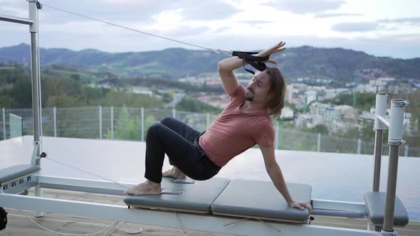 Man doing yoga in Wheel pose on pilates reformer