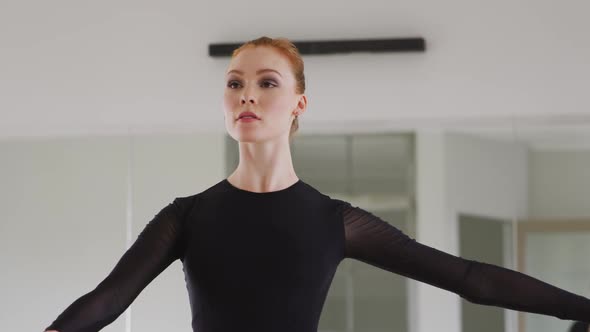 Caucasian female ballet dancer practicing ballet during a dance class in a bright studio