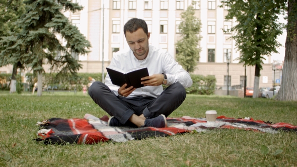 Man Reading Book Outside In The Park