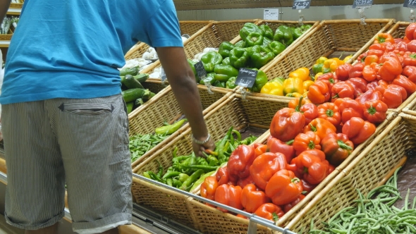 Indian Man Is Choosing Peppers In a Grocery Supermarket. Guy Selecting Fresh Ripe Green Peppers In
