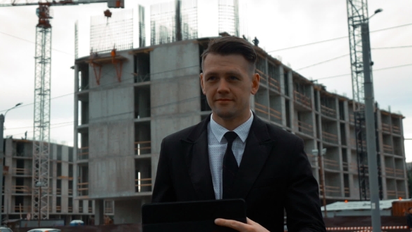 Businessman Using Digital Pad Near New Construction