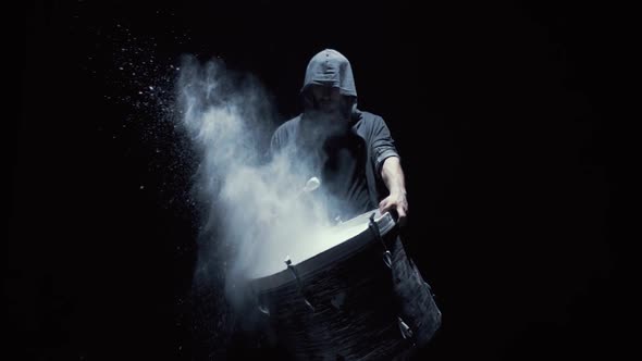 Hooded Man Beats Drum with Flour