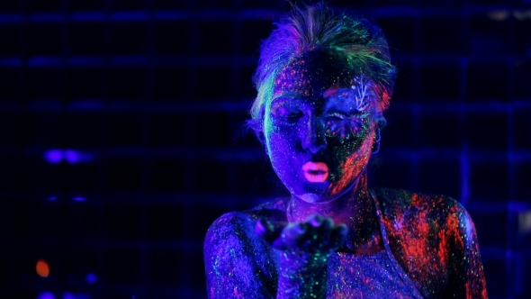 Girl In Ultraviolet Light Blows Pink Fluorescent Powder With Palm