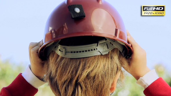 A Young Boy Wearing a Hard Hat Outdoors.