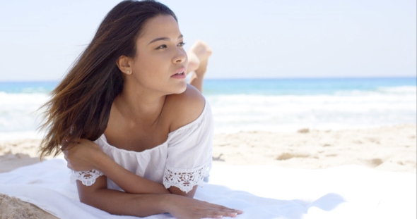 Young Woman Relaxing In The Shade Of An Umbrella