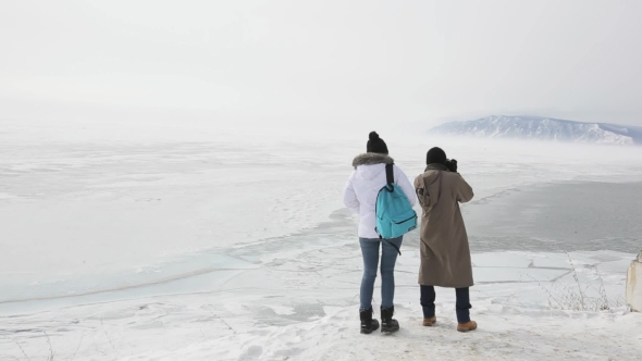 Couple Travelers Visiting Lake With Mountains In Winter And Take Pictures.