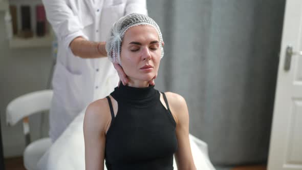 Unrecognizable Beautician Helping Woman Lying Down on Medical Couch in Beauty Salon