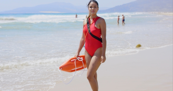 Woman In Lifeguard Outfit On Beach With Swimmers