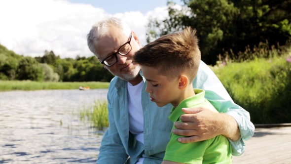 Grandfather And Grandson Sitting On River Berth 24