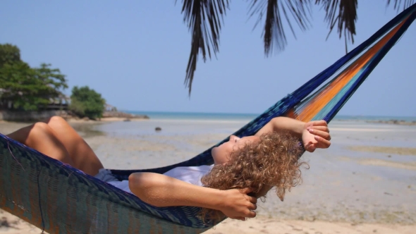 Young Woman Swinging In Hammock On Tropical Beach