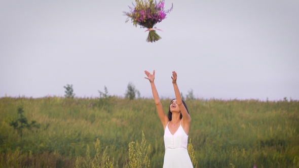 Young Woman Standing On Green Field Throwing a Flower Bunch