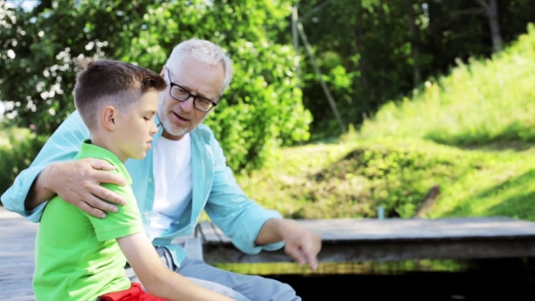 Grandfather And Grandson Sitting On River Berth 26