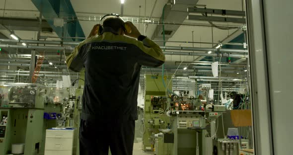 A man in a blue and yellow uniform puts on yellow headphones, walks through the shop_16