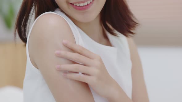 Close up shot Beautiful Asian woman applying moisturizer cream on her shoulder and arm gently.