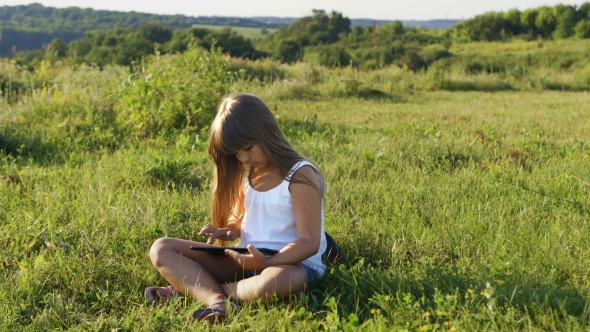 Girl With a Tablet Pc Sitting On The Grass.