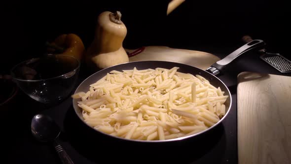 Frying Pan with Raw Pasta Macaroni. Fall in Slow Motion