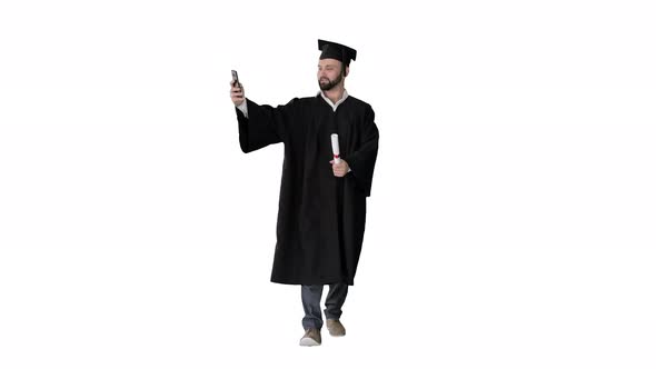 Man Wearing the Graduation Robe Walking and Taking Selfie with Diploma on White Background