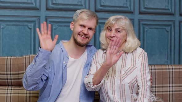 Family of Senior Grayhaired Mother and Handsome Adult Son or Grandson Waving Hi Hello Welcome