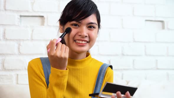 Teenage Asian Girl Applying Makeup While Sitting on Sofa