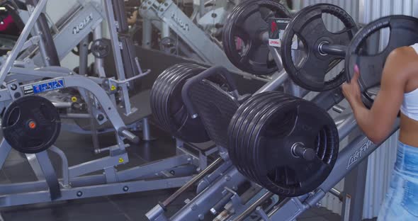 Fitness gym girl sets her weights on a leg press machine at the gym