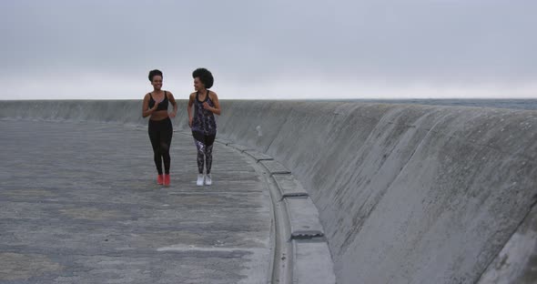 Two mixed race women running on docks