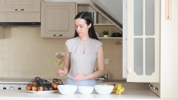 Woman Puts Ripe Fruit in a Plate in the Kitchen