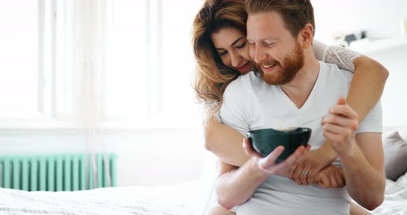 Happy Married Couple Being Romantic in Bed Sharing Cereal