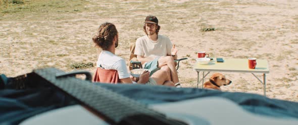 Two men sitting at a camp side table talking