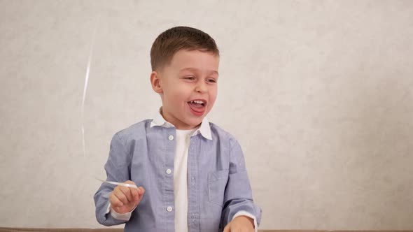 A Blond Boy in a White Tshirt and a Blue Shirt Hits a Purple Ball and Laughs