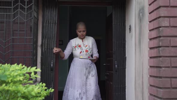 Smiling and hopeful cancer patient bald girl comes out of home with plate full of colored powders af