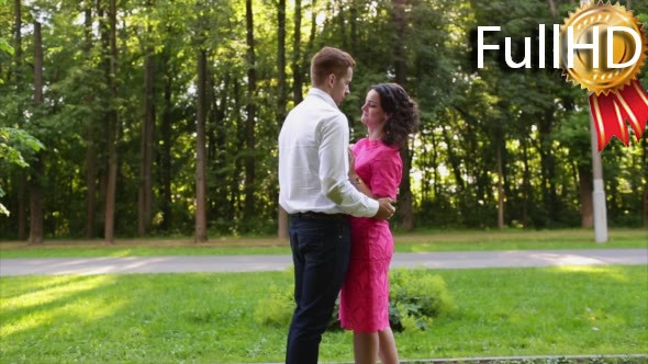 Young Couple Kissing in Park on a Background of