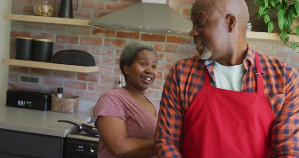 Happy african american senior couple cooking together in the kitchen