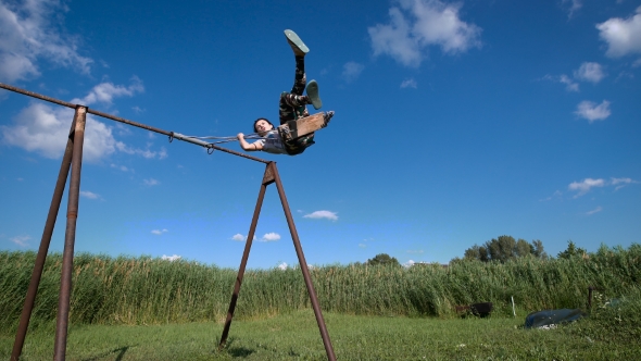 A Young Woman Is Swinging On a Swing At a Green Field.