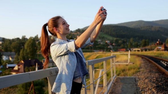 Smiling Beautiful Young Woman Taking Pictures With Smartphone In Mountains