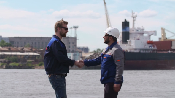 Two Dockers, Coworkers And Colleages Meet And Shake Hands In Shipping Cargo Port