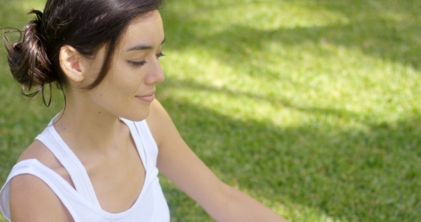 Serene Young Woman Meditating On a Green Lawn