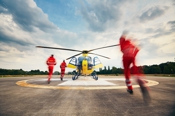  (paramedic, doctor and pilot) running to the helicopter on the heliport.