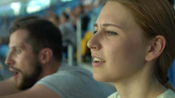 Excited Girl Watches Football Game a Stadium, Applauds and Worries About Team