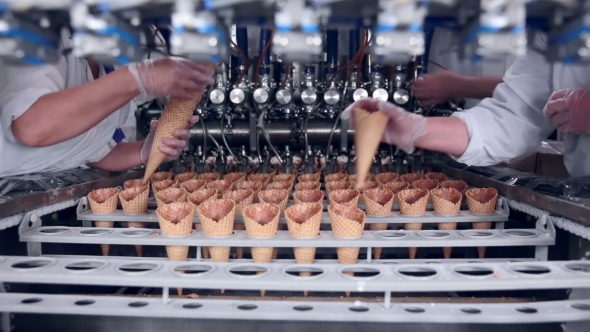 Moving Belt With Ice-cream Cones And a Workers Hands Putting Them. Food Industry.