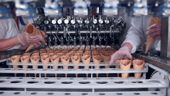 Moving Belt With Ice-cream Cones And a Workers Hands Putting Them. Food Industry.