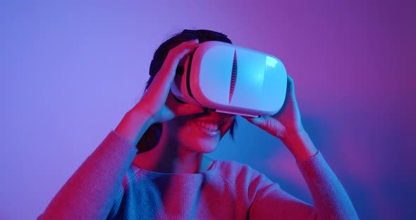 Woman Playing Game with Joystick and Enjoy with Virtual Reality with Pink and Blue Lighting