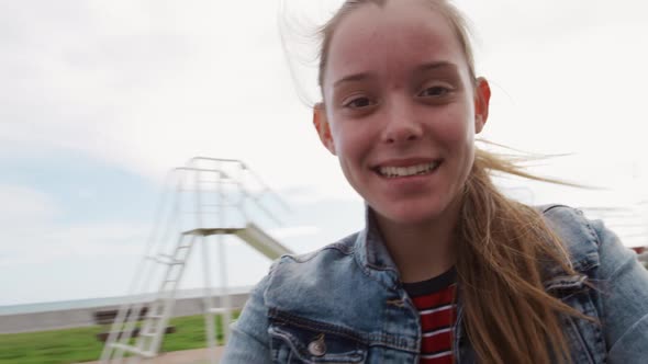 Front view of a Caucasian looking at camera taking selfie on a merry-go-round