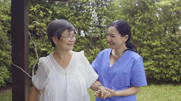 Asian Nurse and Patient Walking in Backyard