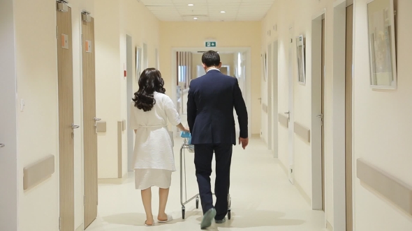 Young Family Walks Down The Hallway Of The Hospital